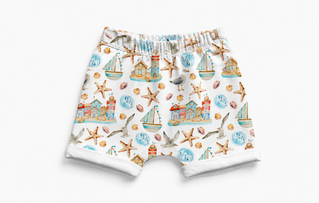 Children's shorts with a nautical pattern featuring boats, seagulls, and lighthouses on a white background.