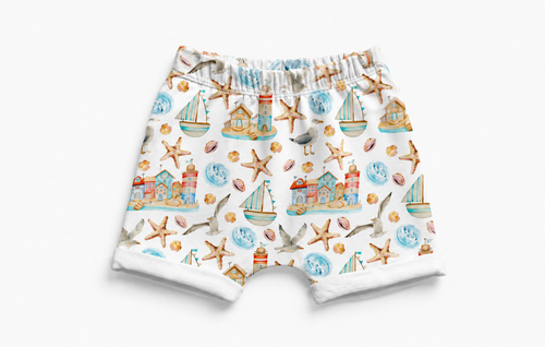 Children's shorts with a nautical pattern featuring boats, seagulls, and lighthouses on a white background.